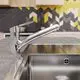 Küchenarmatur mit einem chromierten Auslauf, montiert in einer modernen Küche mit gemusterter Wand und Edelstahlspüle. Ideal Standard Produkt.